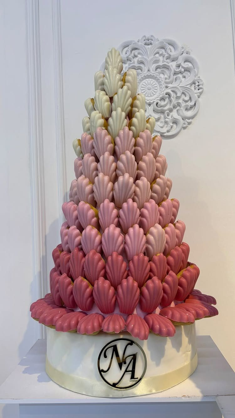 Macaron tower in pink and cream gradients on a white branded base.