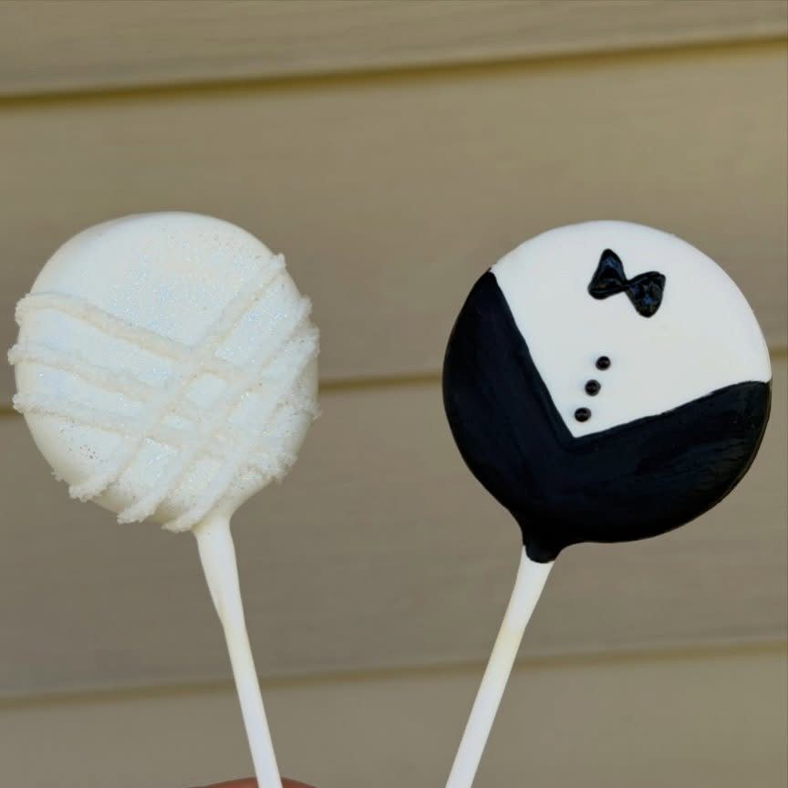 Two wedding cake pops, one white and textured, one decorated as a tuxedo.