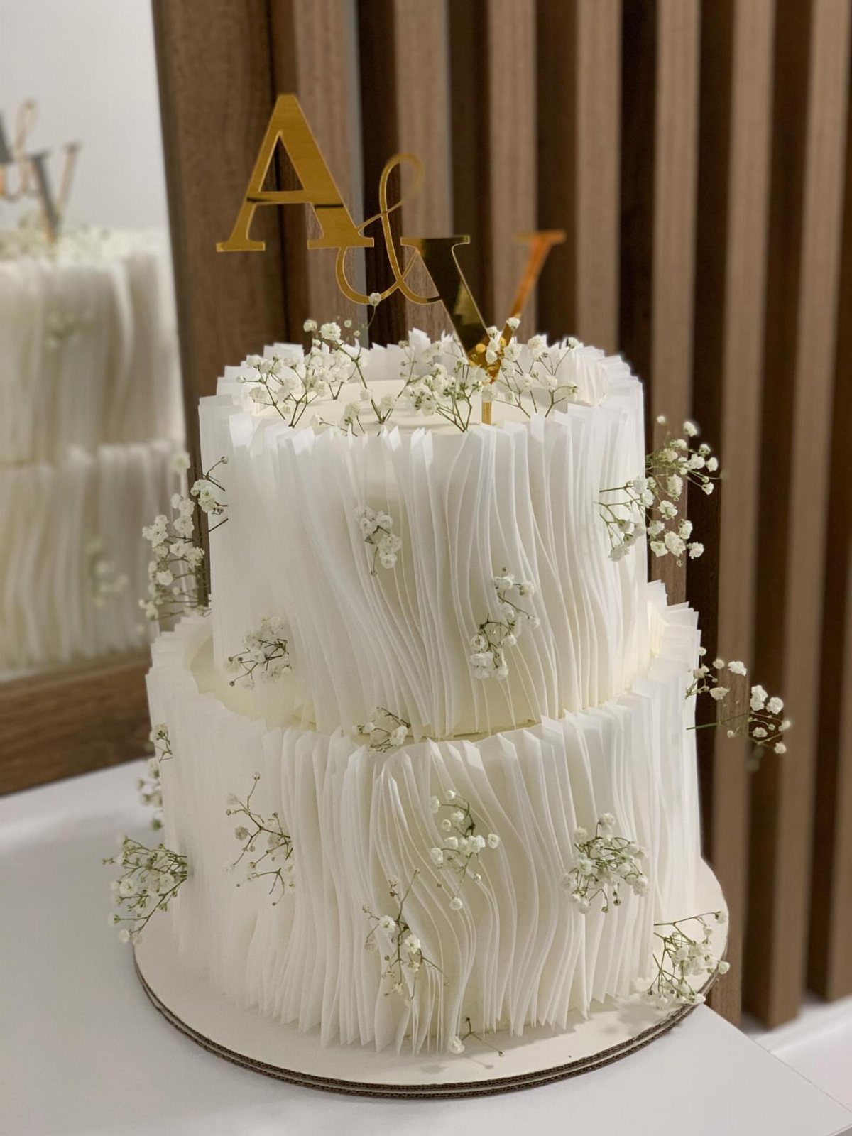 Two-tier white wedding cake with textured frosting and delicate baby's breath flowers.