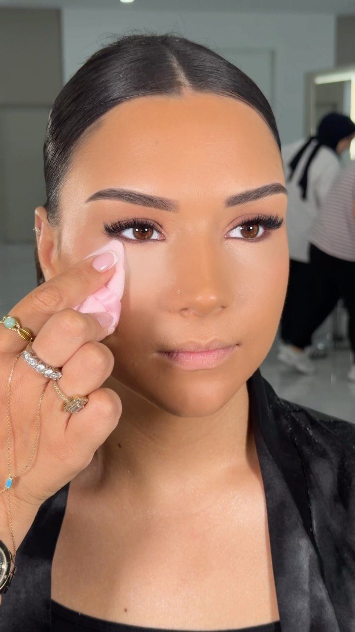 Woman receiving a makeup touch-up with a cotton pad on her cheek