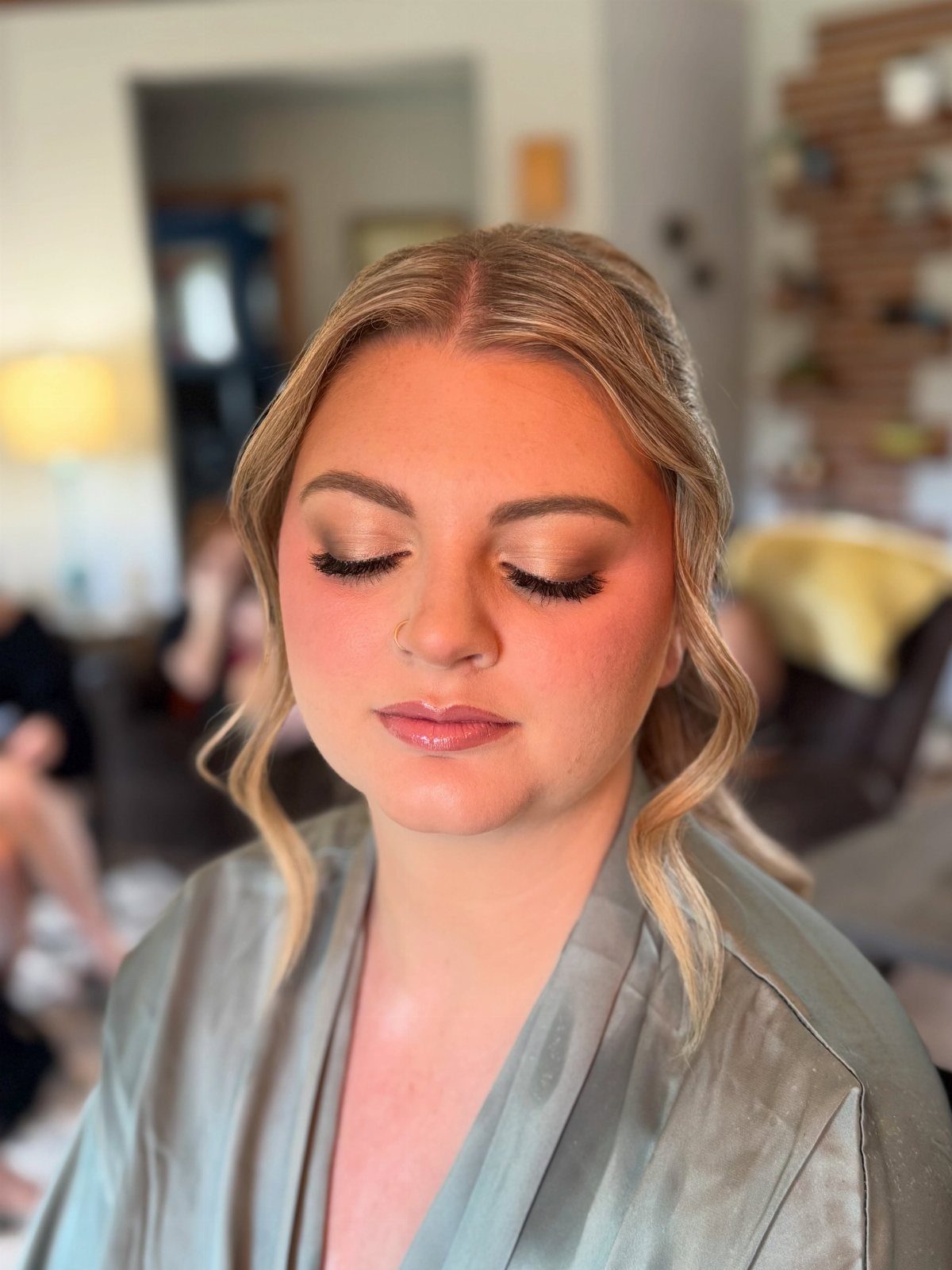Woman with blonde hair wearing a silver robe and shimmering bridal makeup