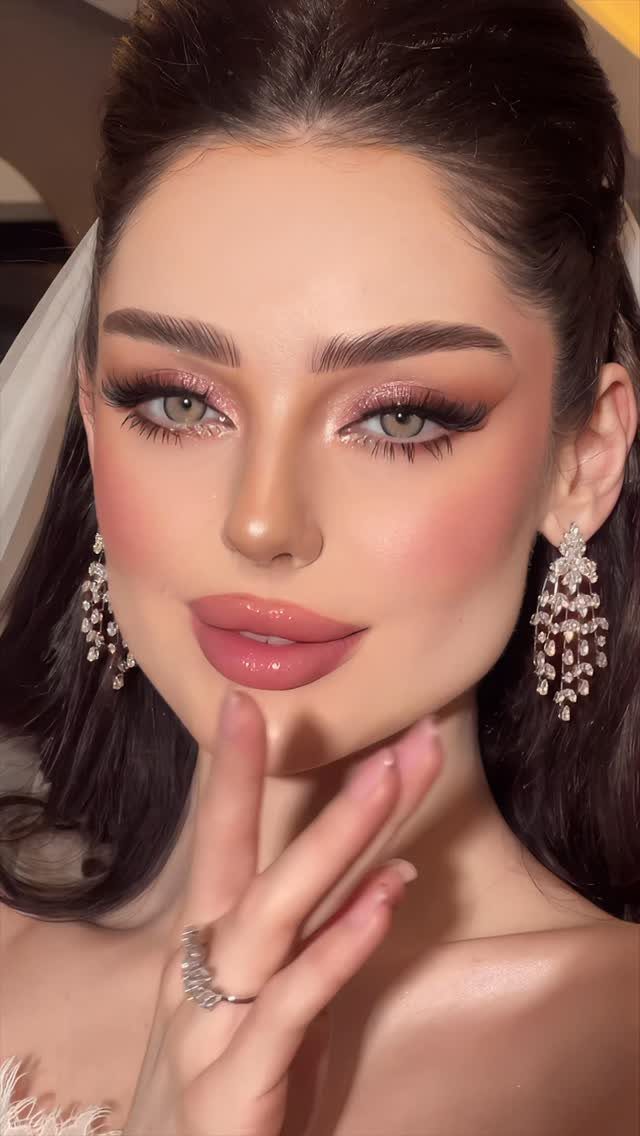 Woman with bridal makeup featuring long false eyelashes and shimmering pink eyeshadow.