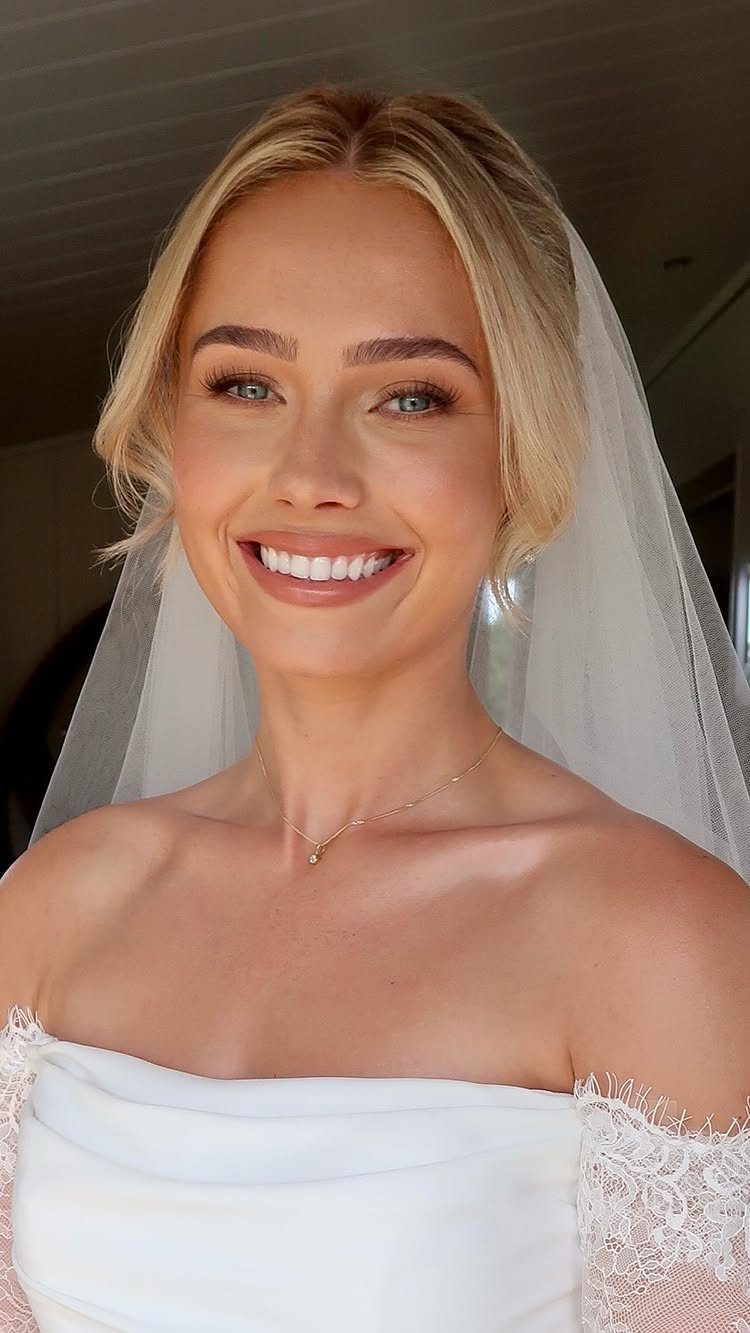 Blonde bride in a white lace dress and veil with natural bridal makeup