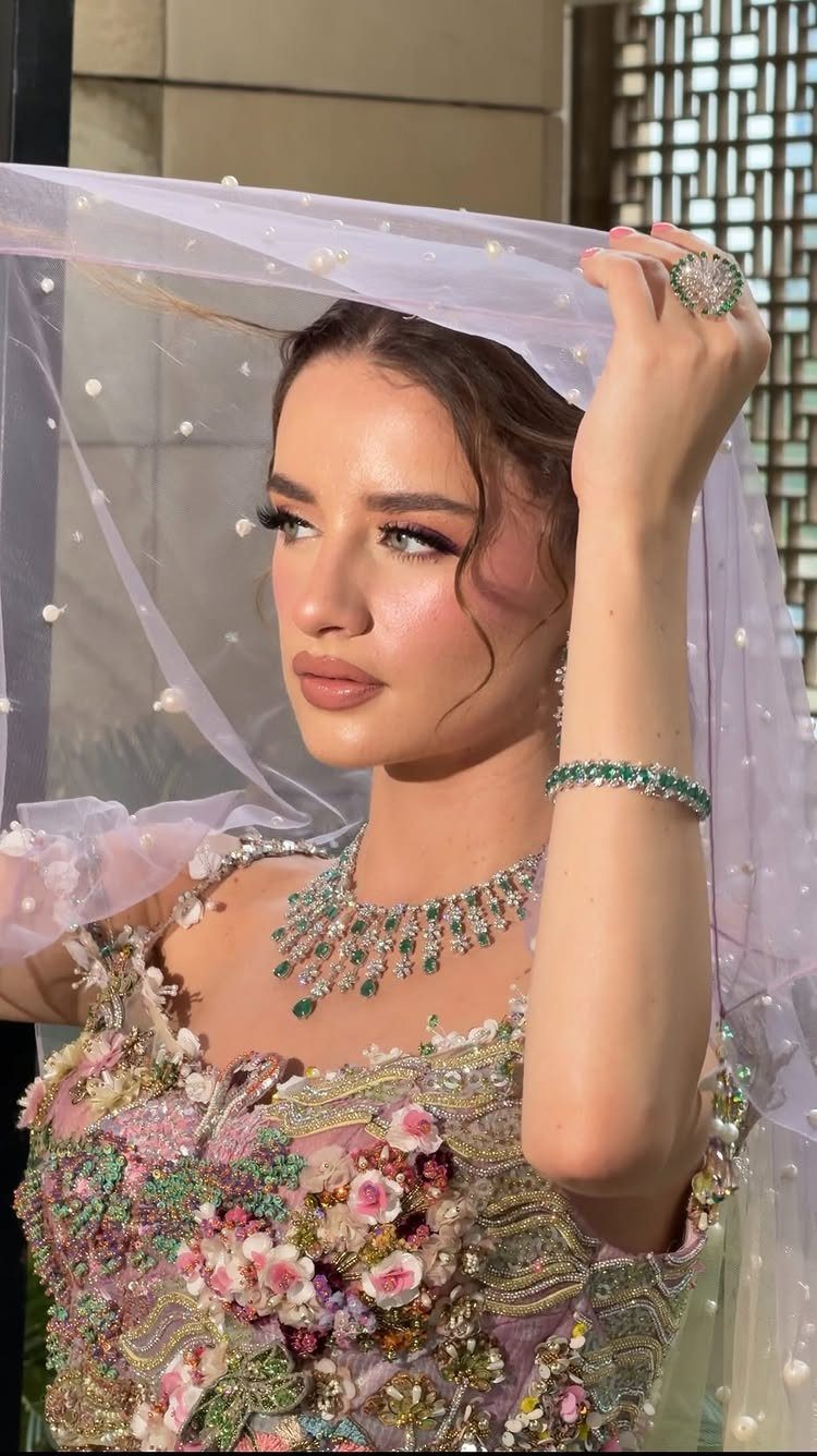 Woman with bridal makeup wearing a floral gown and sheer pearl-embellished veil