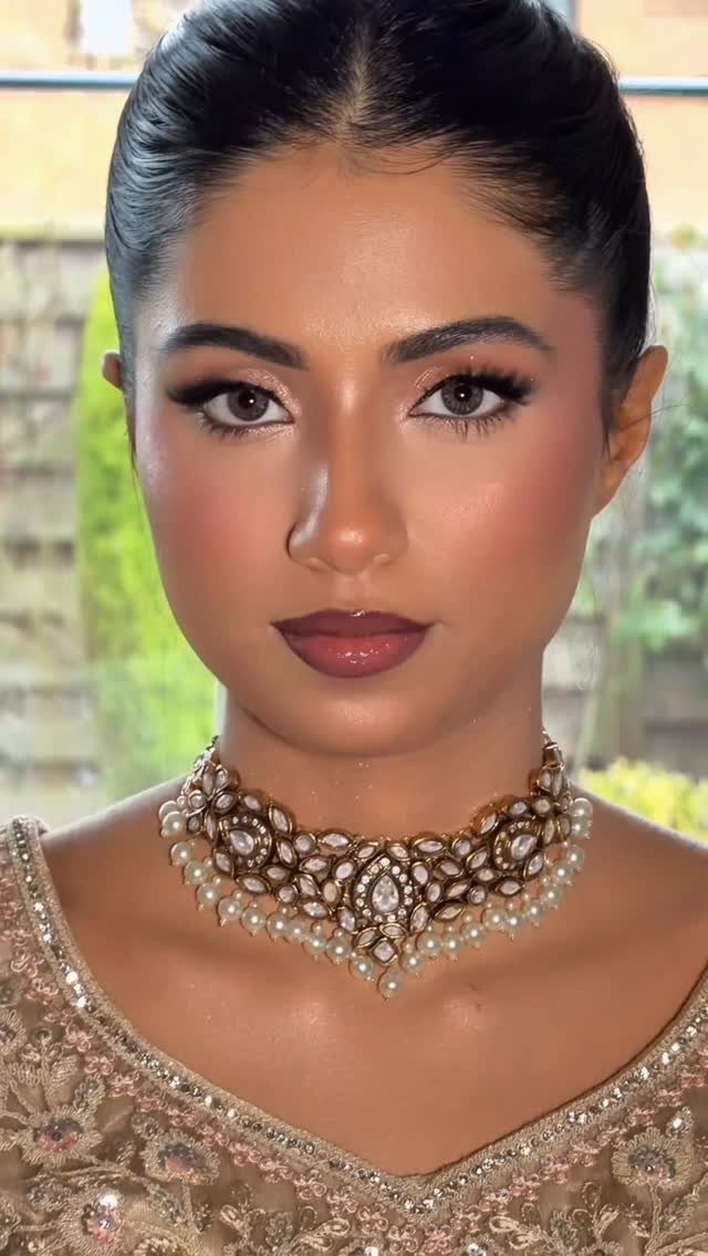 Woman with full bridal makeup wearing an ornate gold and pearl necklace