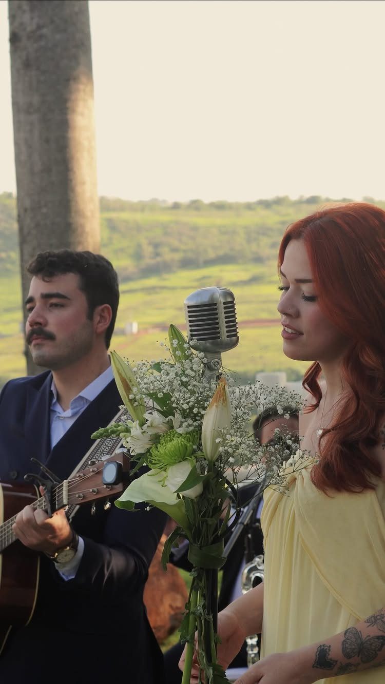 Musicians playing acoustic guitar and singing into a vintage microphone at a wedding.