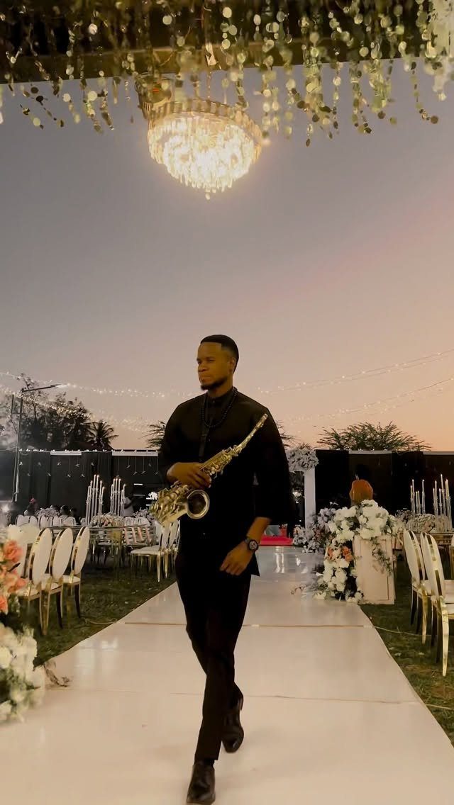 Saxophone player in black suit walking through an elegant outdoor wedding dinner venue