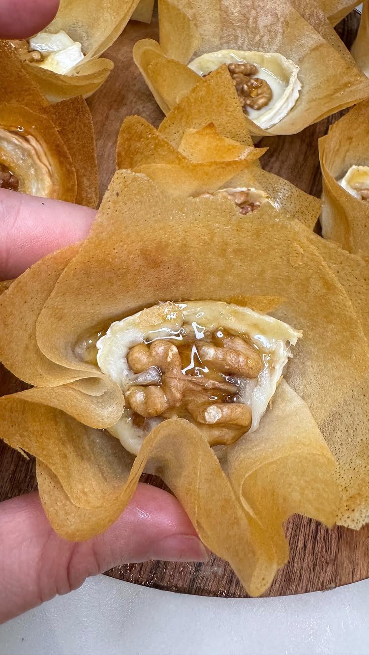 Phyllo pastry cups filled with melted cheese and topped with glazed walnuts.