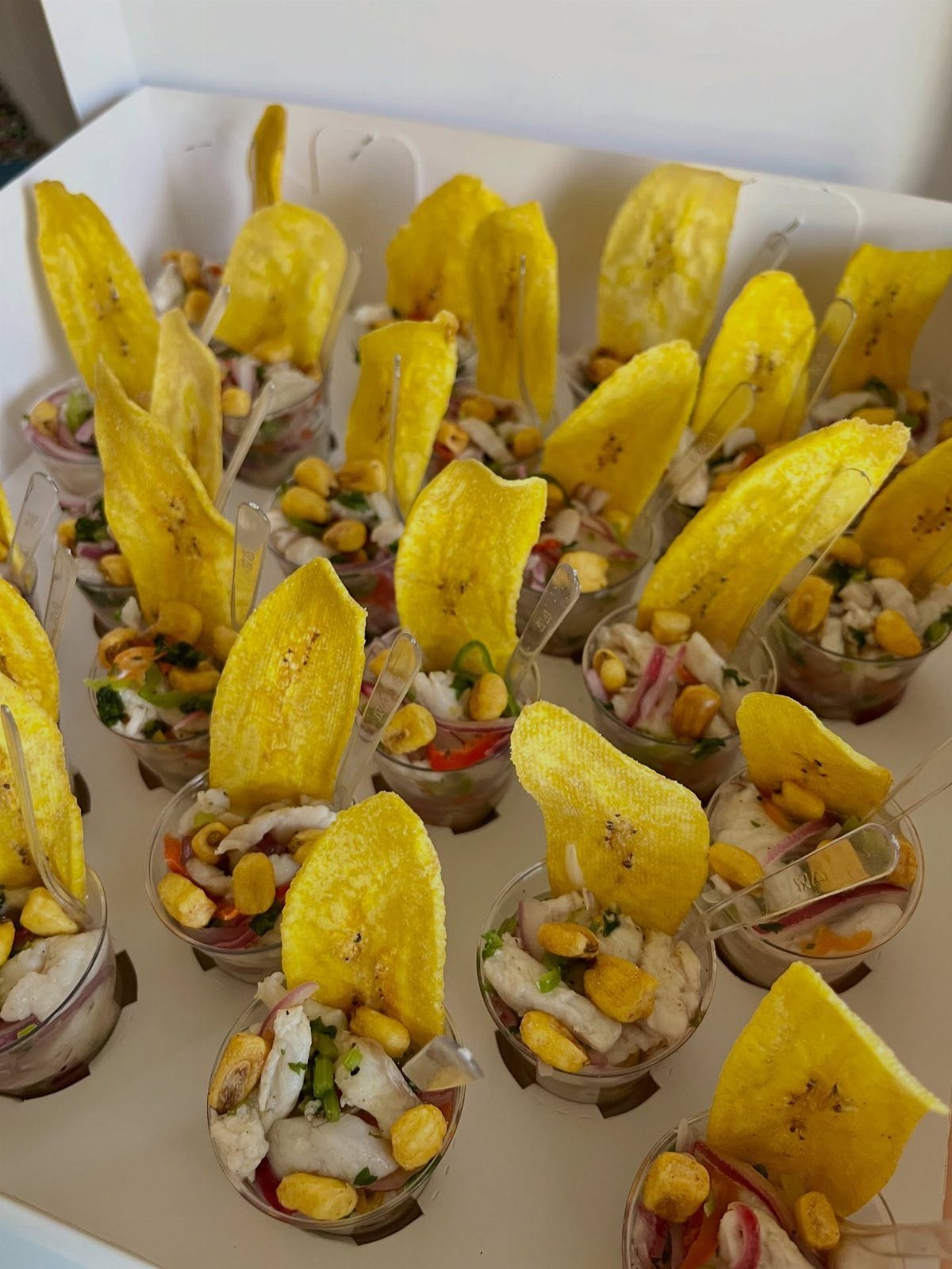 Ceviche shooters with corn and red onion topped with yellow plantain chips