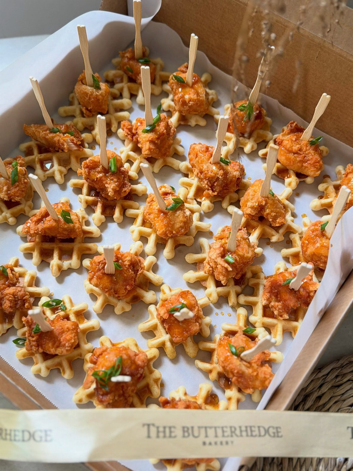Fried chicken and waffle sliders with toothpicks in a bakery box