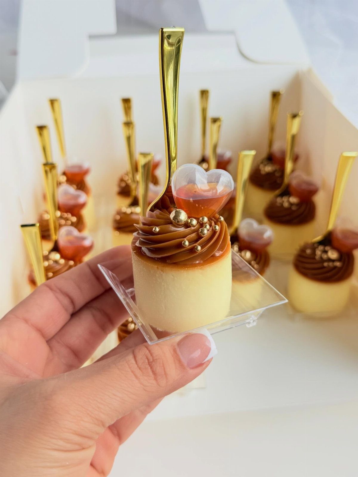 Small cream-colored dessert topped with brown frosting and a heart-shaped jelly garnish