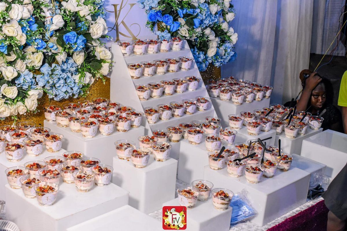 Layered yogurt and fruit bites in small cups on white tiered displays.