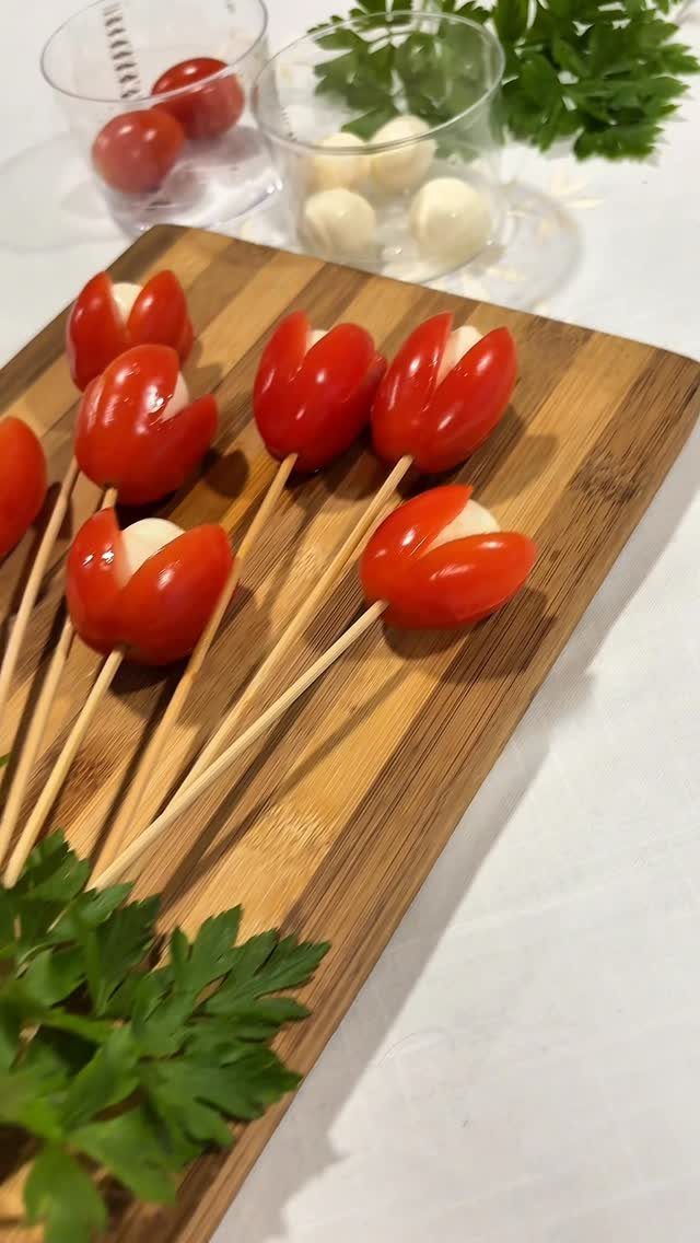 Mini Caprese skewers with tomato tulips and mozzarella on a wooden board.