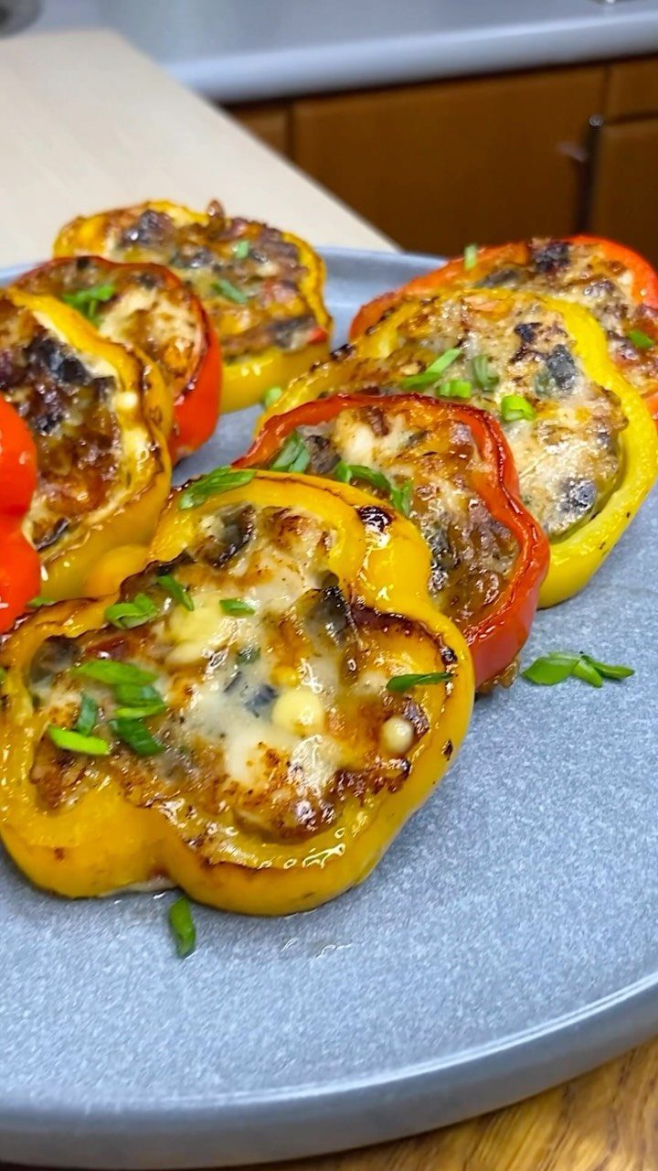 Stuffed mini bell peppers with melted cheese and green onions on a platter