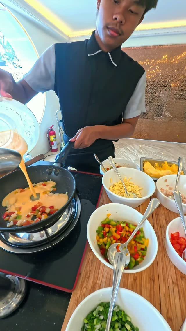 Chef preparing food at a live cooking station with bowls of fresh vegetables