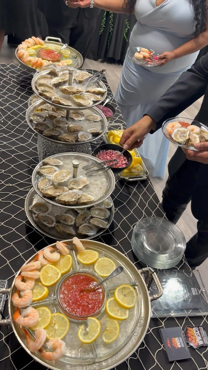 Seafood station with tiered oyster displays and shrimp platters at a formal event.