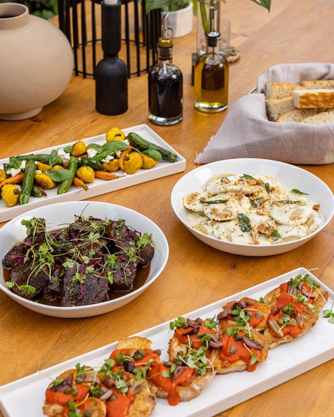 Gourmet shared platters of meat, fish, and vegetables on a wooden table.