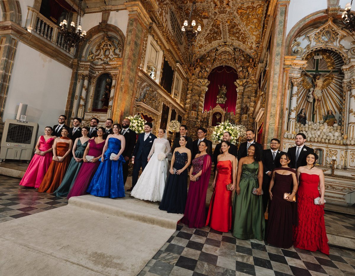Wedding party posing in a gold ornate church with bride and groom centered.