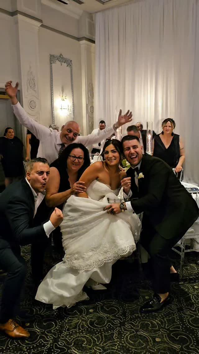 Bride in white gown posing with funny expressions with four wedding guests indoors.
