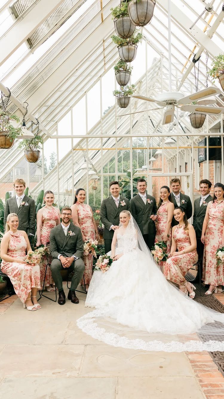 Wedding party posing in a glass conservatory with the bride and groom centered.