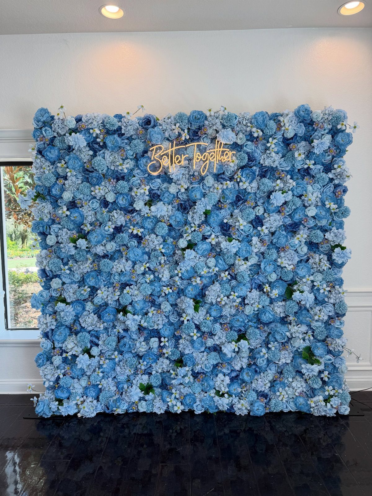 Blue flower wall backdrop with a gold neon Better Together sign indoors