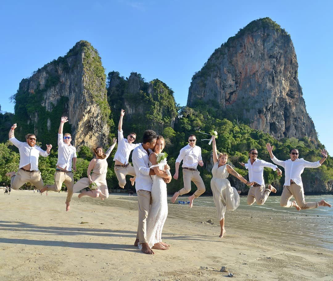 Wedding party jumping in the air around a couple on a tropical beach.
