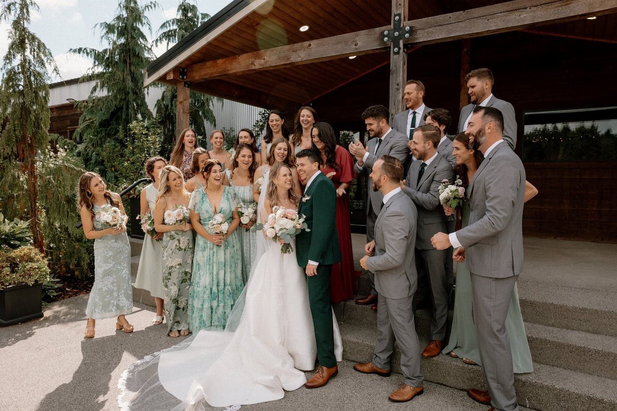 Wedding party posing on concrete stairs with the bride and groom centered.