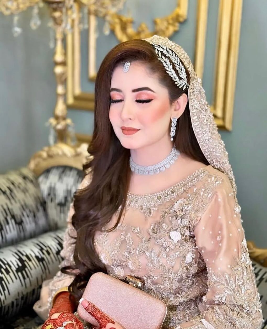 Woman with long brown wavy hair wearing a jeweled headpiece and bridal gown
