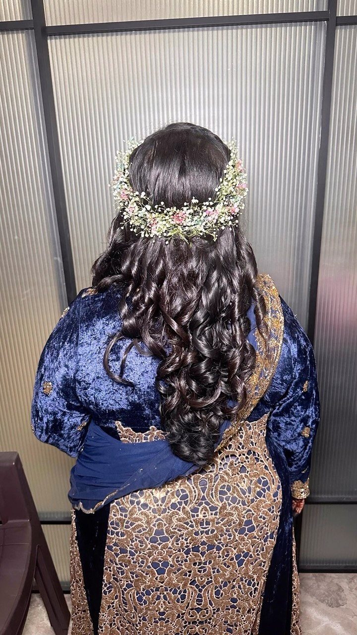 Long dark curly hair adorned with a pink and white floral crown