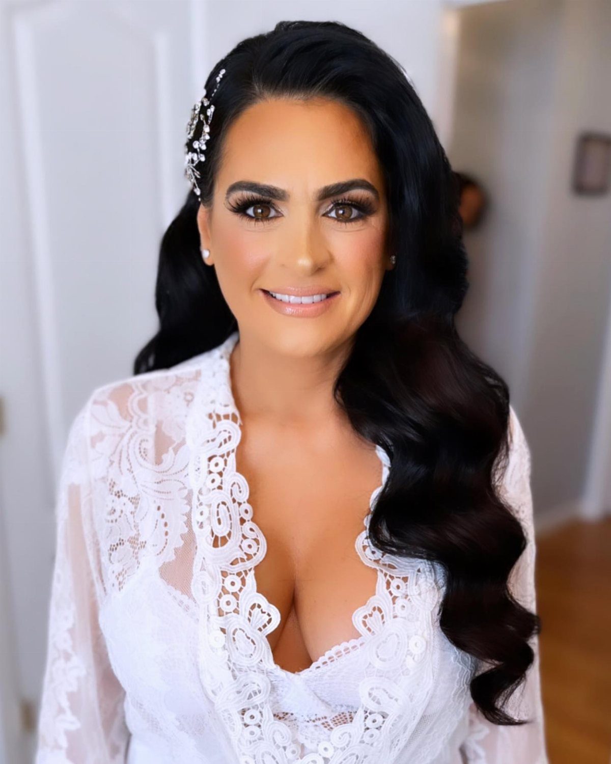 Woman with long dark wavy hair and a sparkling hair accessory wearing lace.
