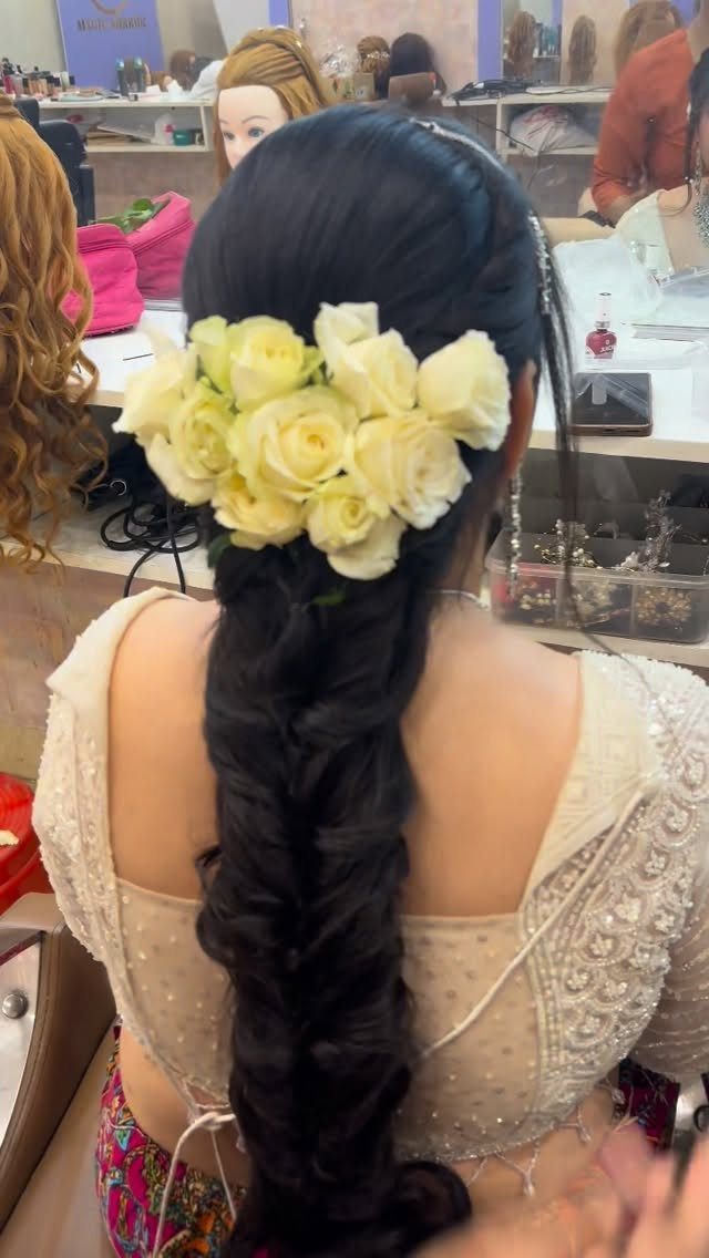 Dark braided hair decorated with a cluster of fresh white roses from behind.