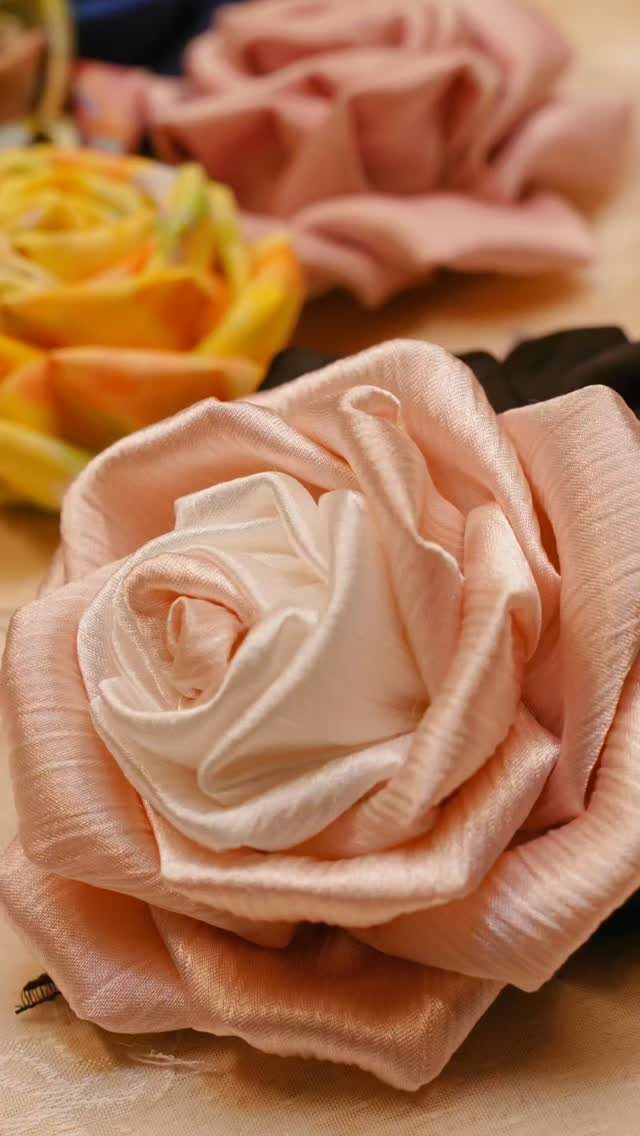 Handmade silk roses in pink and yellow-orange tones resting on a light surface.