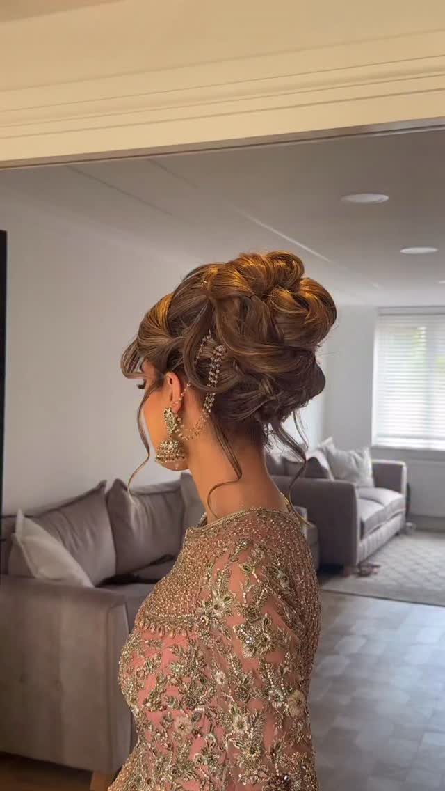 Woman with a curly updo adorned with gold beads and embroidered dress.