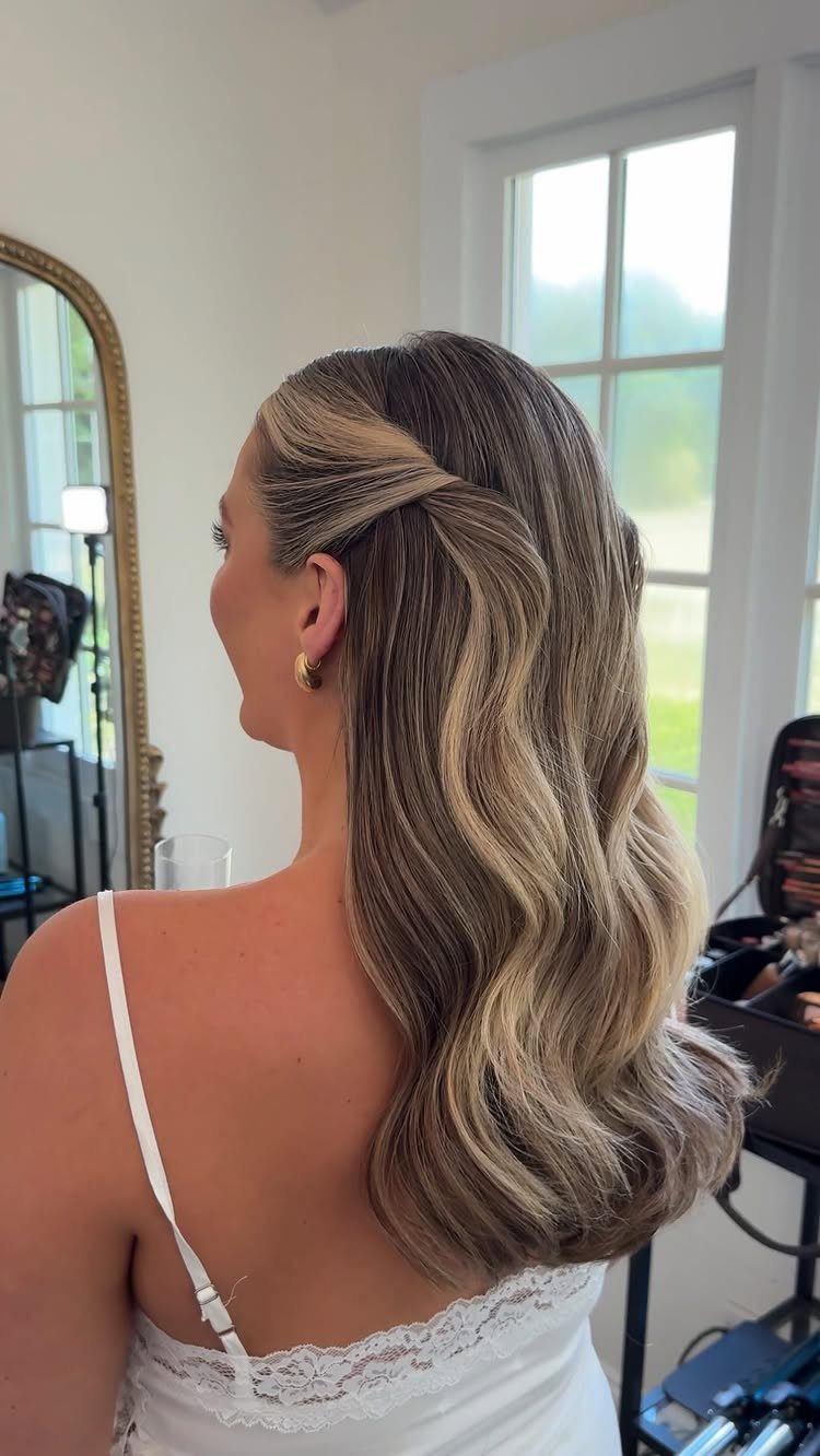 Woman with highlighted hair in a half-up half-down style with soft waves.