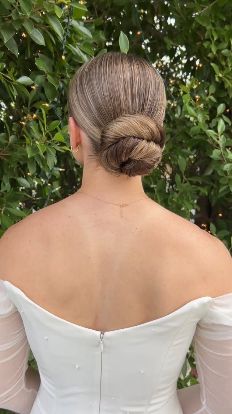 Woman with blonde hair in a low knotted bun wearing a white wedding dress