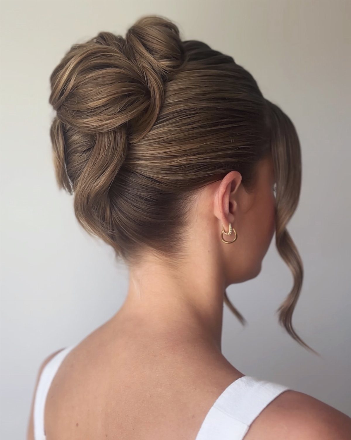 Brown hair styled in a twisted updo with a loose face-framing curl.