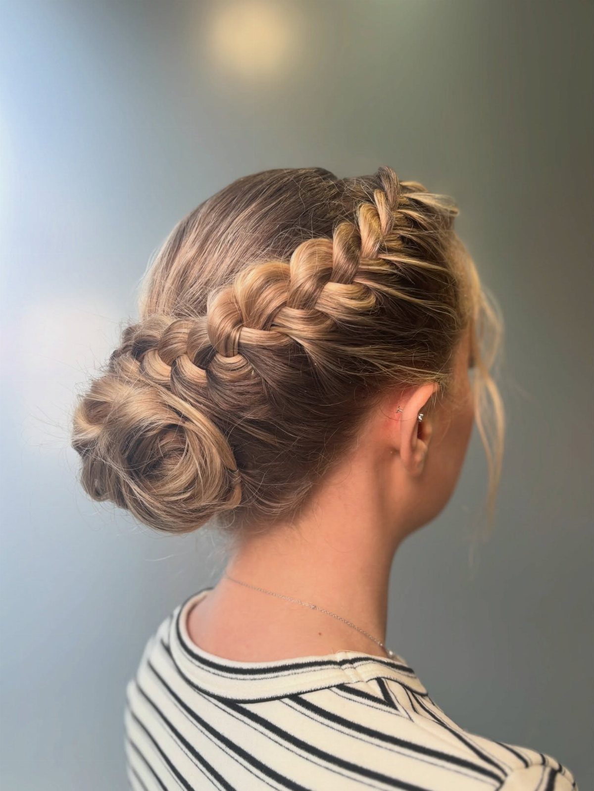 Blonde hair styled in a thick side braid ending in a low bun.