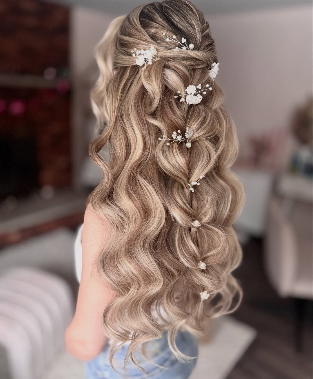 Blonde wavy hair in a half-updo decorated with small white floral pins