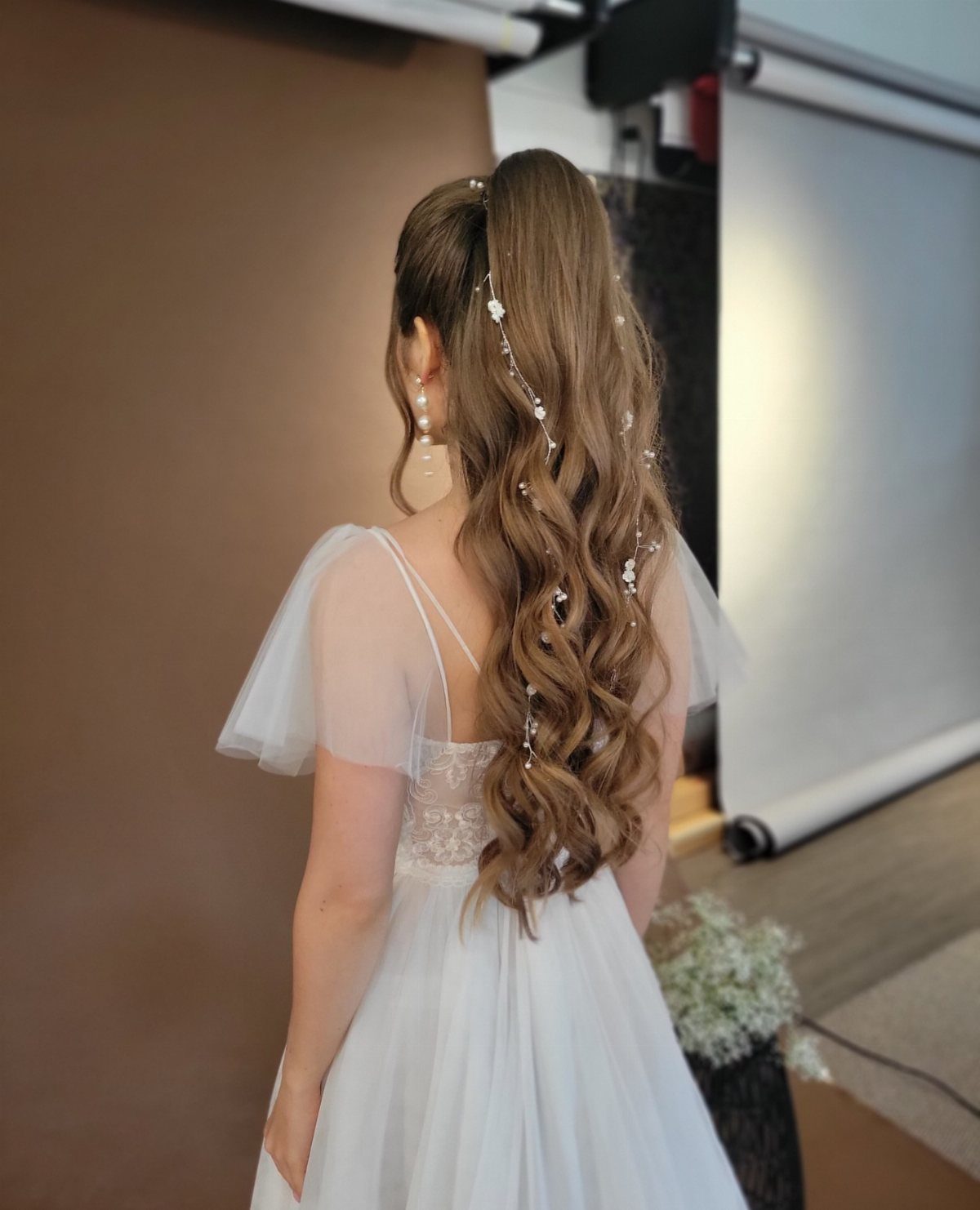 Woman in white wedding dress with a high ponytail and long romantic curls.