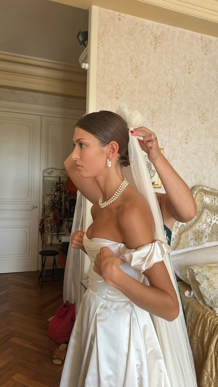 Bride with slicked back low bun wearing a white satin wedding dress and veil