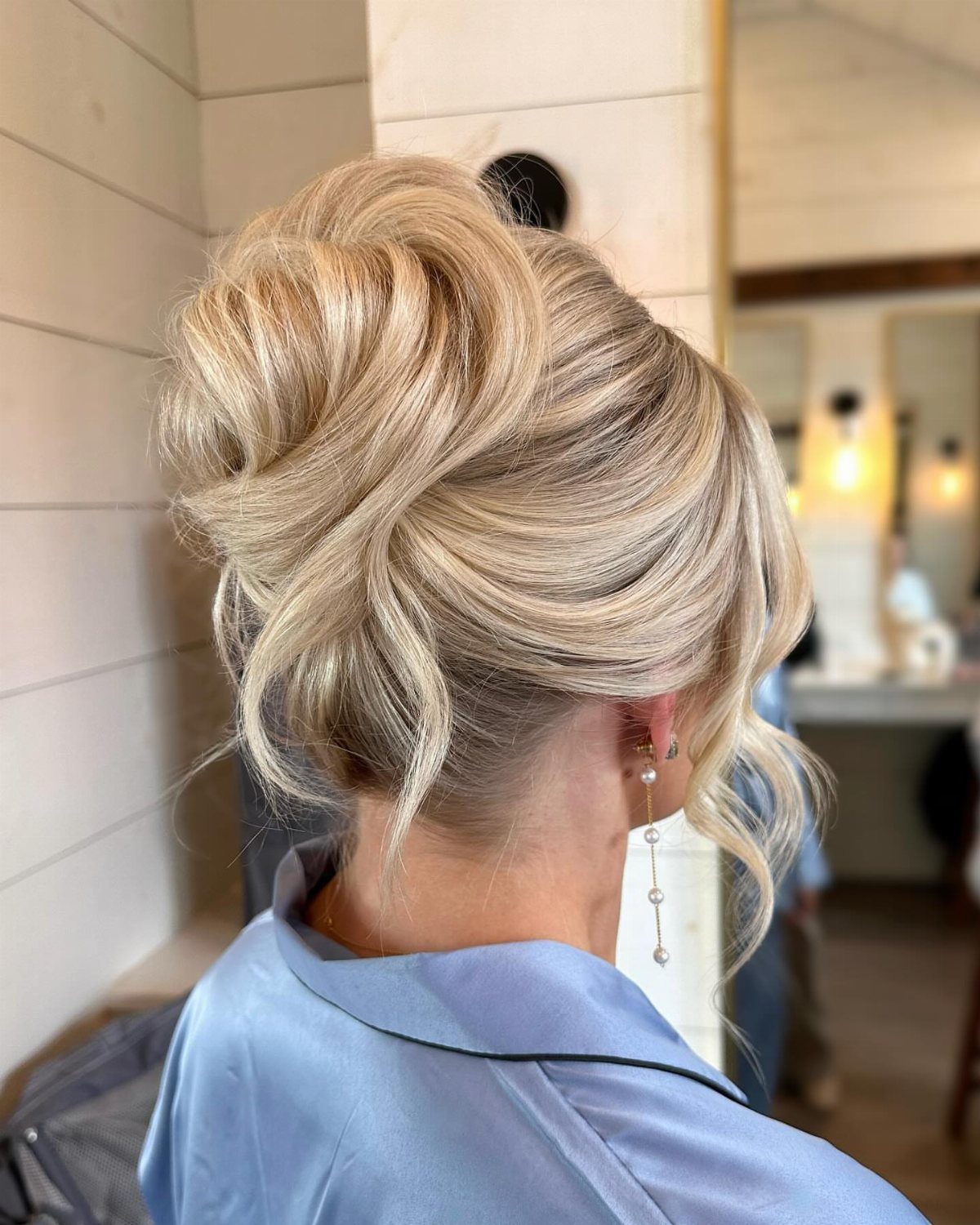 Blonde twisted updo hairstyle on a woman wearing a blue satin robe.