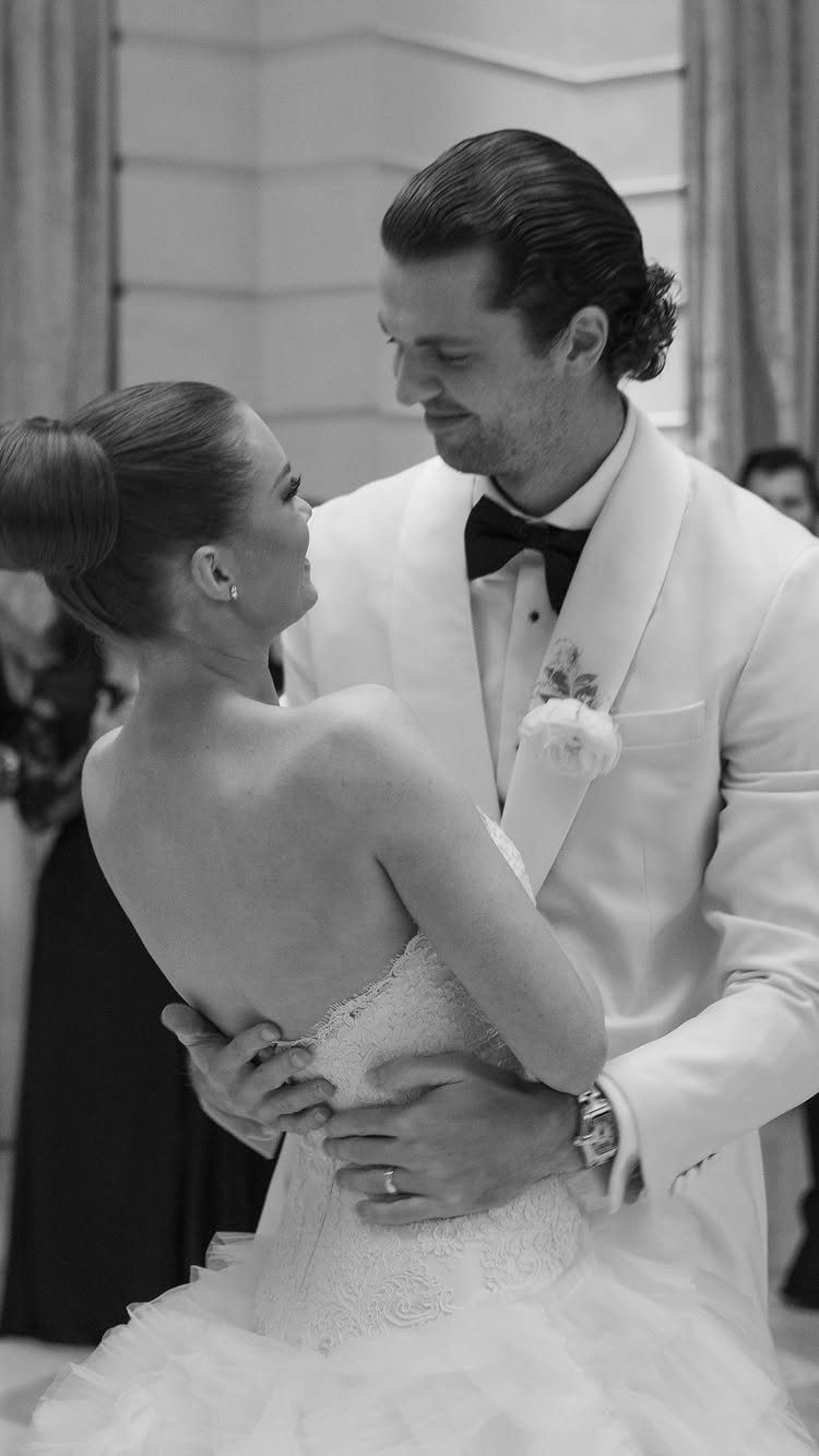 Bride and groom dancing together in formal wedding attire during their first dance.