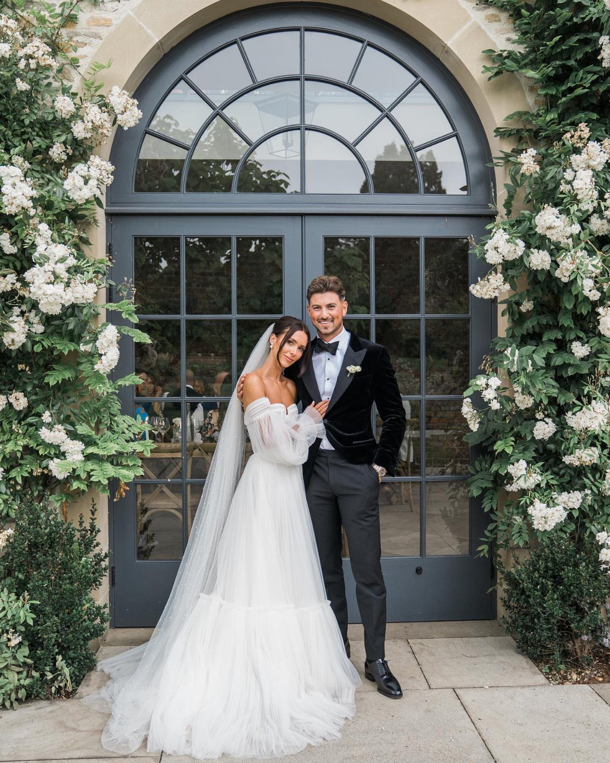 Bride and groom smiling and posing together in front of an arched doorway