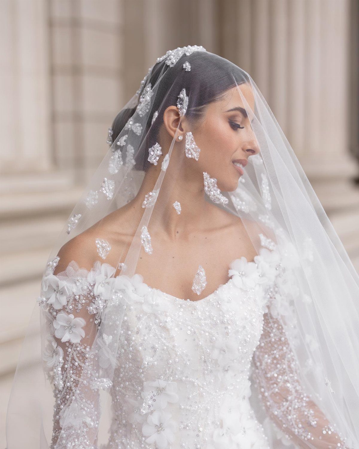 Bride in a white floral wedding dress wearing a sheer embroidered veil