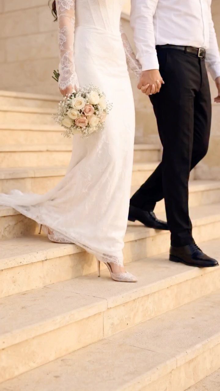 Bride and groom holding hands while walking down stone stairs during a wedding.