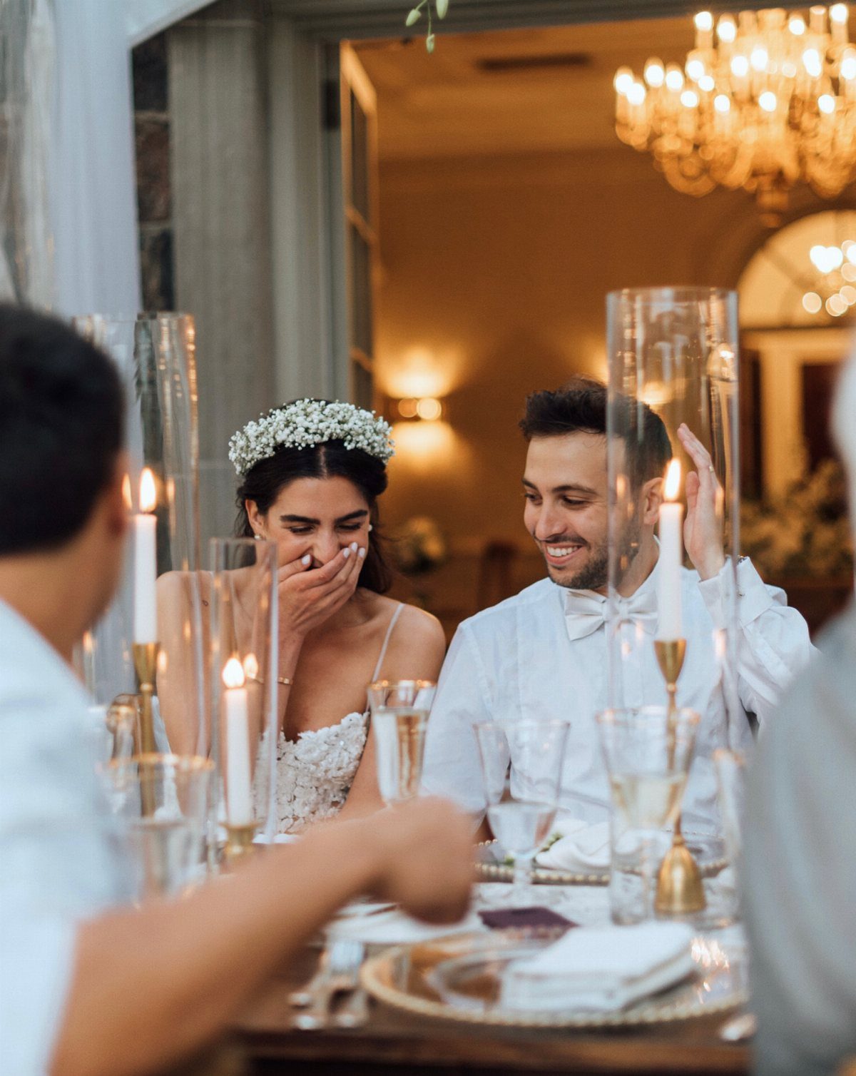 Bride and groom laughing together at a candlelit wedding reception table.