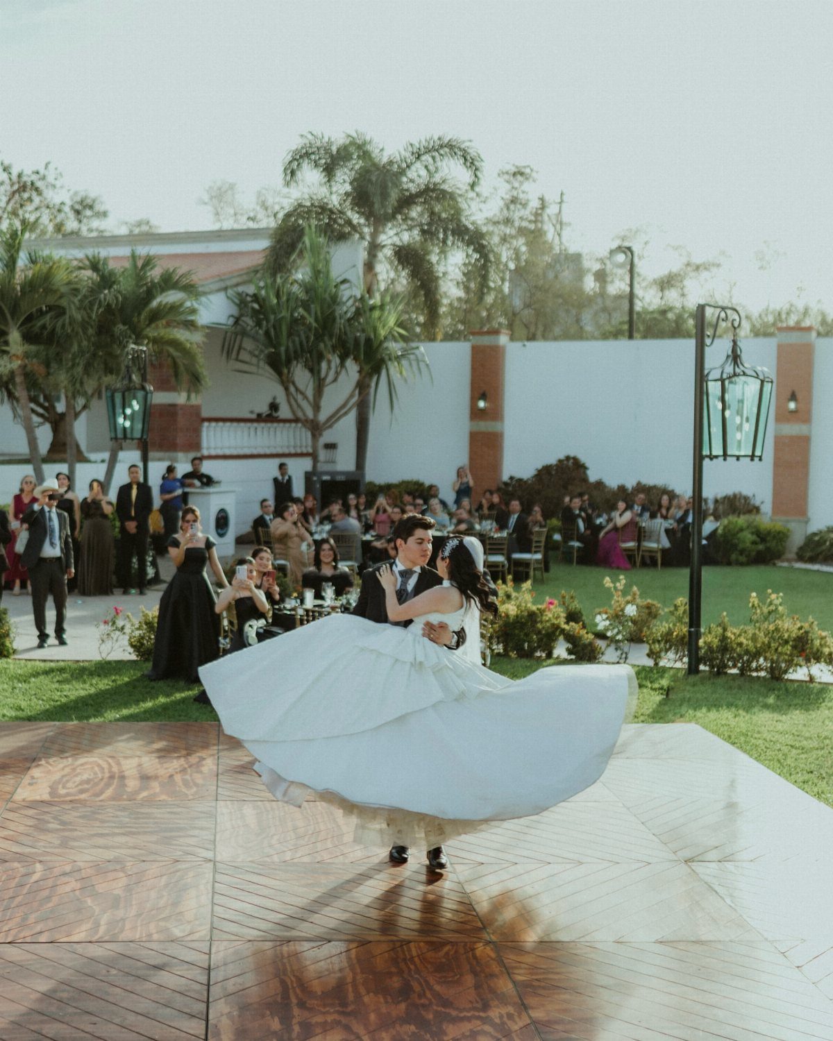 Bride and groom dancing on a wooden floor during their wedding reception outdoors.