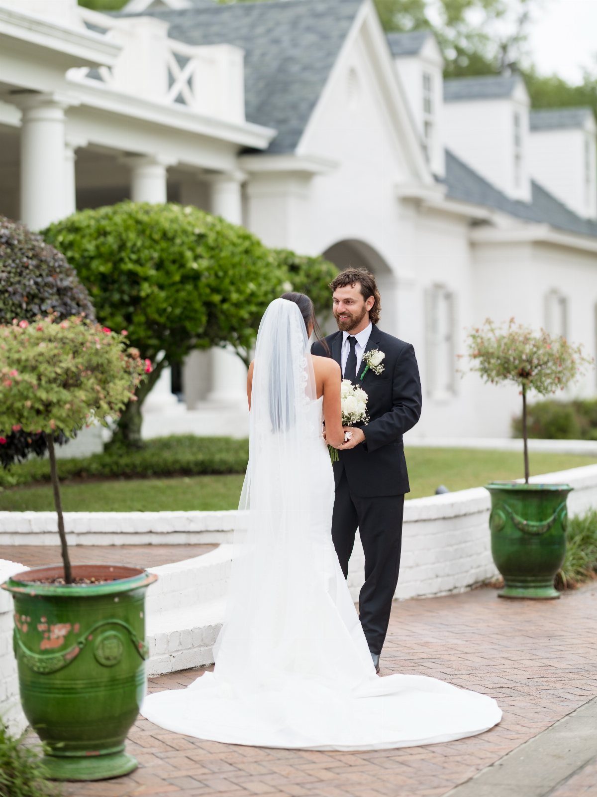 Bride and groom facing each other during a first look in front of a house