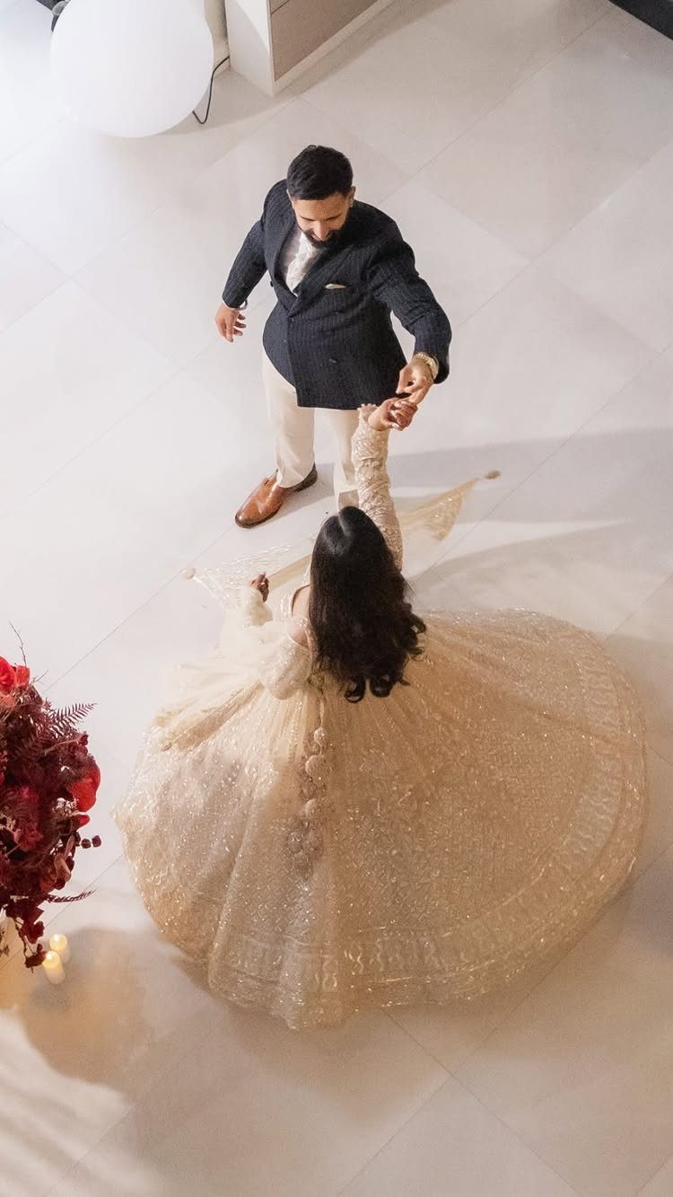 Bride in a shimmering cream gown twirling while held by her groom.