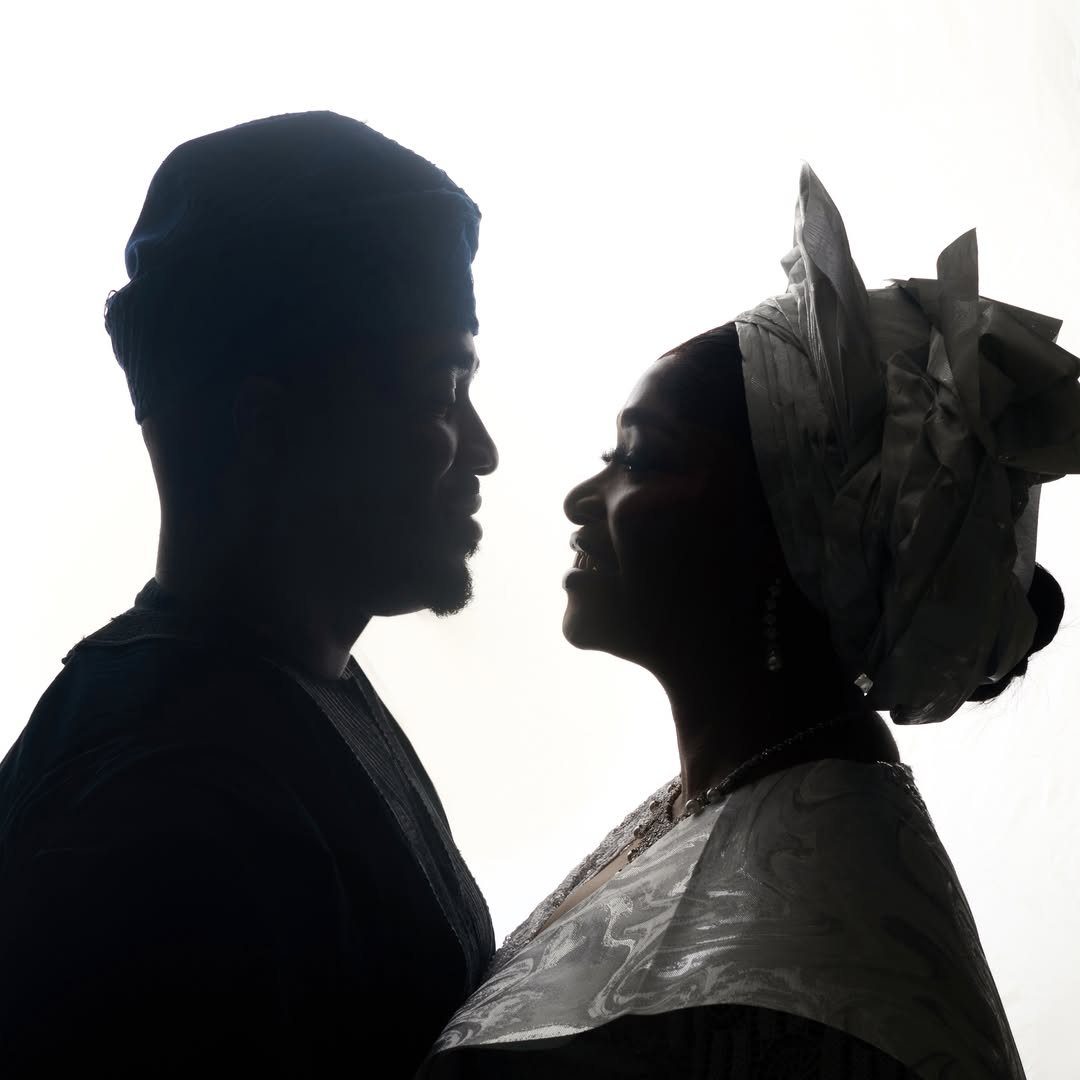 Silhouetted couple facing each other against a bright white background in profile view.